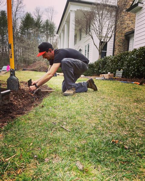 Technician installing low-voltage lighting wiring in a yard