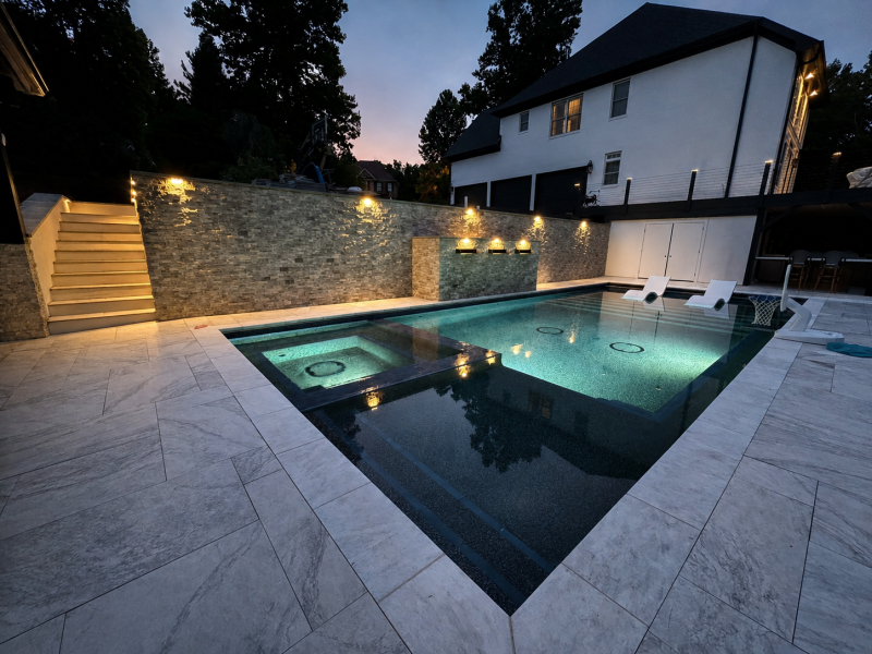 Backyard pool with landscape and pool lighting at dusk