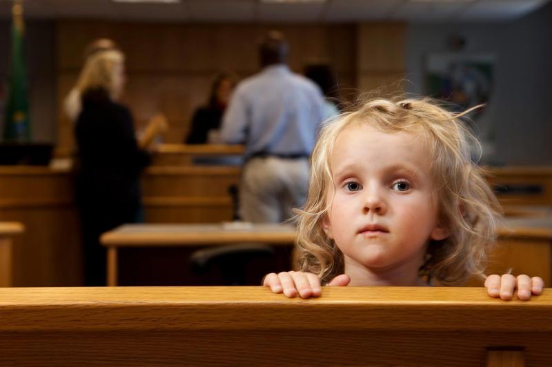 Child looking over a bench in a court room